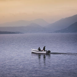 Men on boat at lake against sky