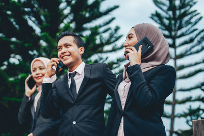 Happy young man holding camera while standing outdoors