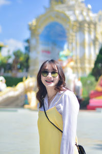 Portrait of young woman wearing sunglasses while standing in city