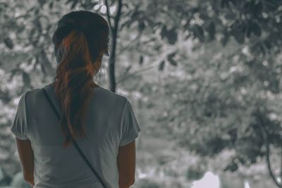 Rear view of mature woman standing against trees