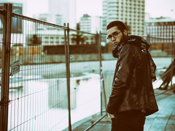 Portrait of young man standing in city during winter