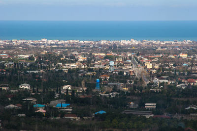 High angle view of illuminated city by sea against sky