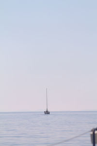 Sailboat sailing in sea against clear sky