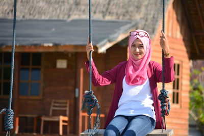 Portrait of young woman swinging on sunny day