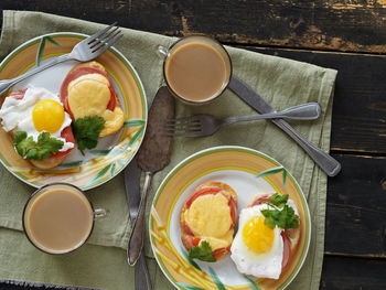 Varieties of toasted sandwiches with sausage, tomatoes, cheese and eggs on plates.