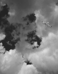 Low angle view of airplane flying against cloudy sky