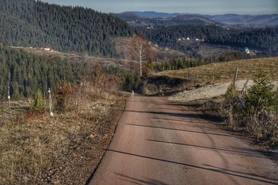 Dirt road amidst plants and mountains against sky