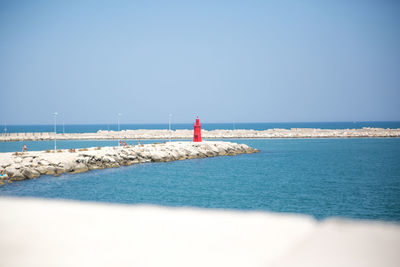 Lighthouse by sea against clear sky