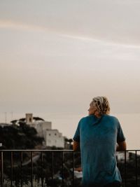 Rear view of man looking at city against sky