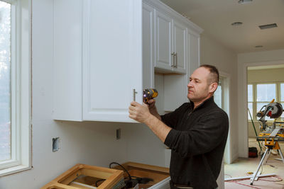 Man drilling cabinet at home