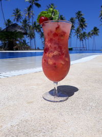 Close-up of red wine glass on swimming pool