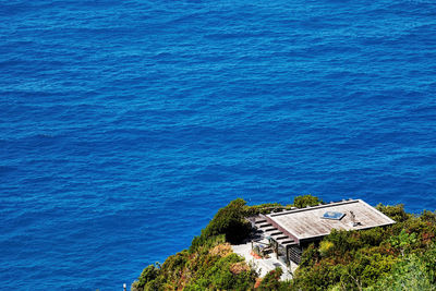 High angle view of built structure amidst trees on mountain by blue sea