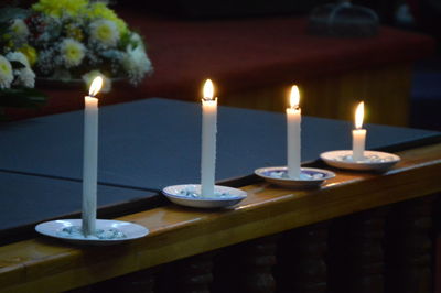 Close-up of lit candles on table in illuminated building