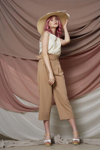 Full length of young woman standing in hat