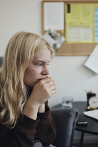 Thoughtful depressed blond teenage girl sitting in school office