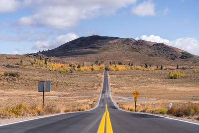 Empty road by mountain against sky