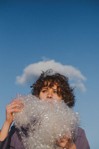 Woman looking away with plastic against blue sky