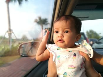 Cute baby girl looking through window in car