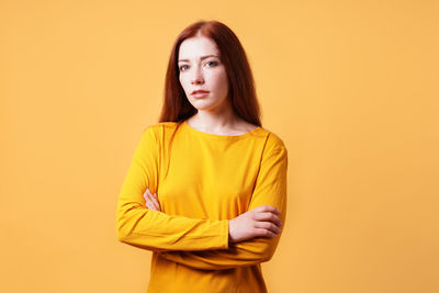 Young woman standing against yellow background