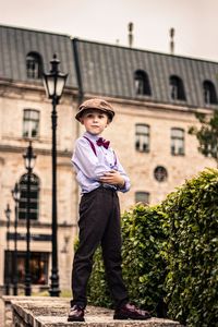 Side view of young man standing against trees