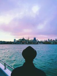 Scenic view of river in front of buildings against cloudy sky