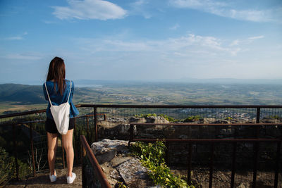 Rear view of woman standing on bridge over sea