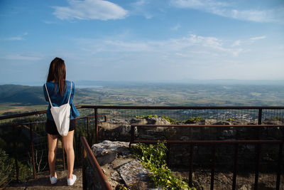 Rear view of woman standing at observation point against landscape