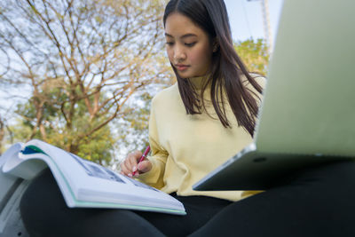 Low angle view of teenage girl sitting on book