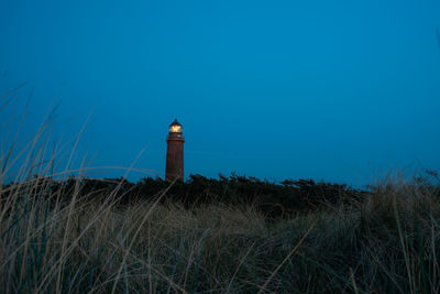 Lighthouse on field against sky