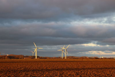 Wind turbines on field against sky