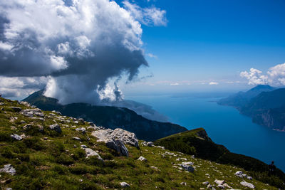 View of lake garda between rocks, clouds and blue sky on monte altissimo di nago in trento, italy