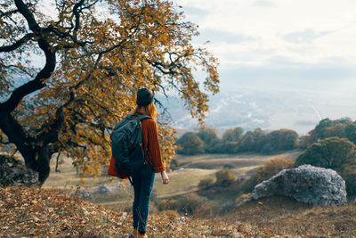 Rear view of man standing on rock against sky