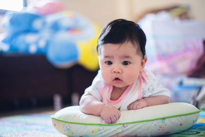 Cute baby girl lying on pillow at home