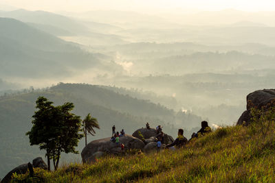 People sitting on landscape against mountains