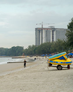 People on beach against sky in city