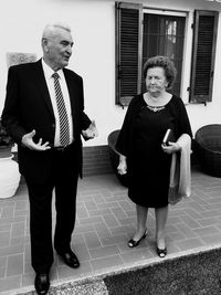 Senior man and woman in formalwear talking while standing on sidewalk