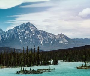 Scenic view of lake by snowcapped mountains against sky