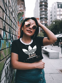 Portrait of smiling young woman standing against wall