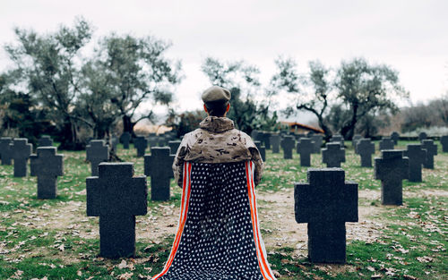 Rear view of people in cemetery against trees