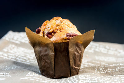 Close-up of fresh walnut muffin on fabric against black background