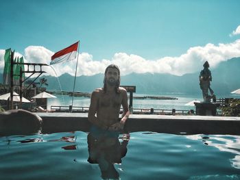 Man swimming in pool by sea against sky