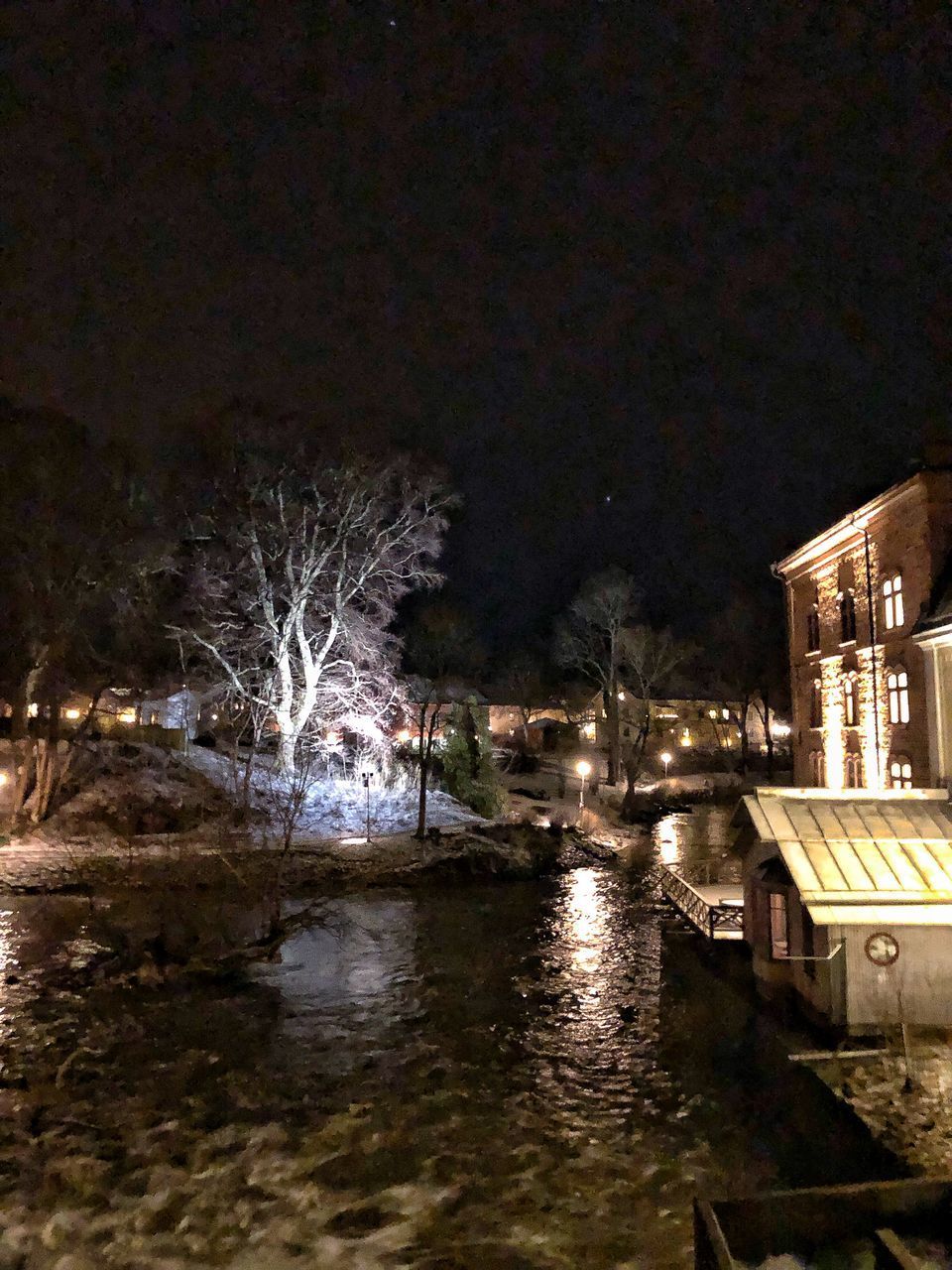 RIVER BY ILLUMINATED BUILDINGS IN CITY