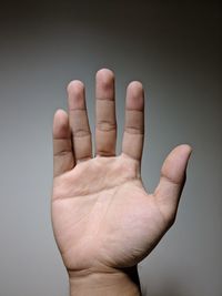 Cropped hand of man against gray background