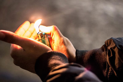 Cropped image of hand igniting cigarette lighter