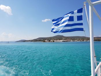 Scenic view of beach against blue sky and greek flag