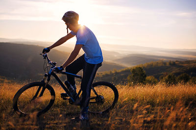 Side view of male cyclist with bicycle on mountain