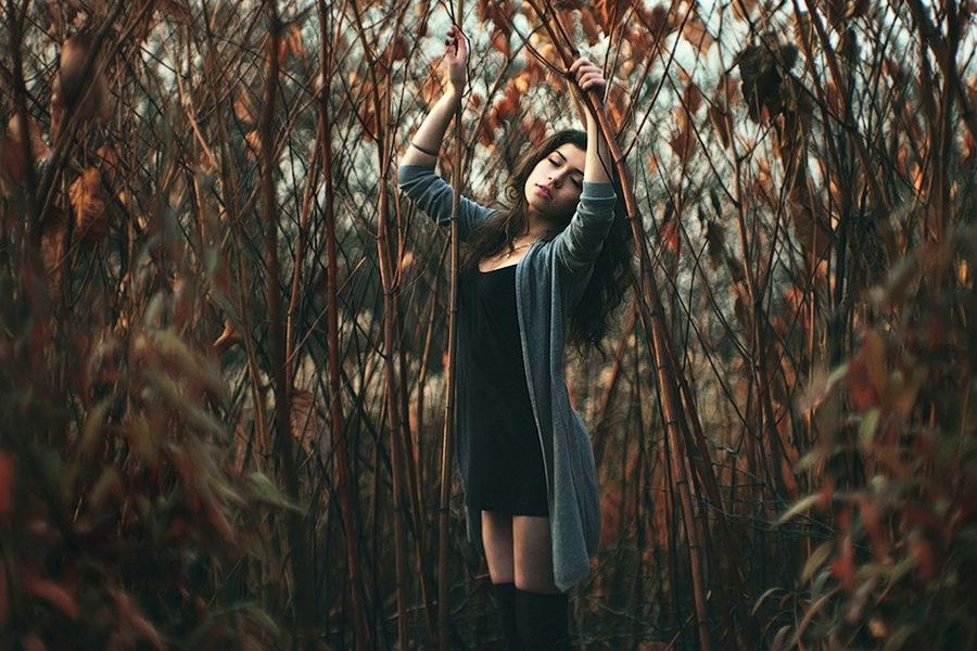 YOUNG WOMAN STANDING ON TREE TRUNK