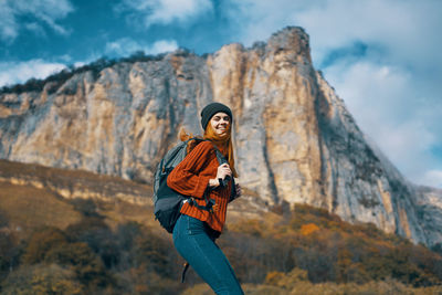 Full length of young woman looking away against mountain