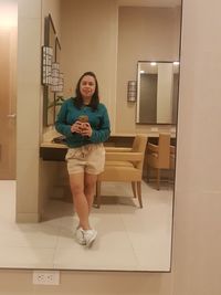 Portrait of woman standing against tiled floor at home