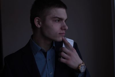 Close-up of young man smoking over black background